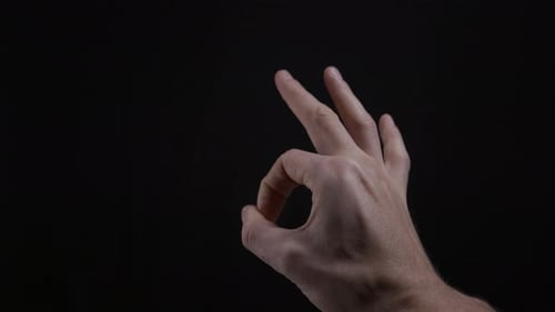 Hand Making Okay Sign in Studio on Black Background