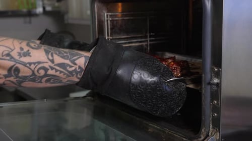 Le chef sort des côtes de porc cuites du four dans la cuisine Côtes levées juteuses