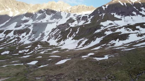 Aerial drone footage flying forward and turning through a dramatic, jagged mountain landscape with r