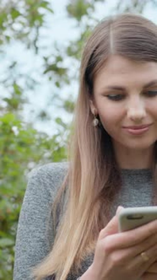 Woman Uses Smartphone Outdoors in Natural Setting
