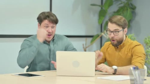 Two Men Celebrate Success at Office on Laptop