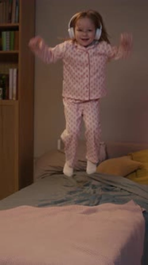 Excited Girl Jumping on Bed with Headphones