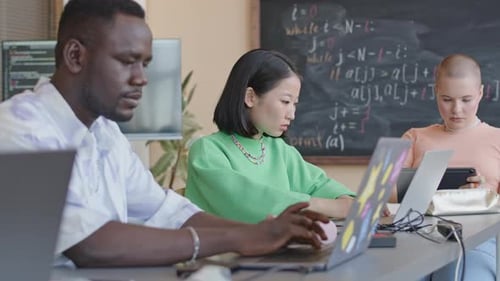 Multiethnische College-Studenten programmieren während des Unterrichts auf Laptops