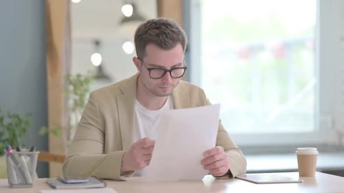 Man in Office Reviewing Documents With Pen