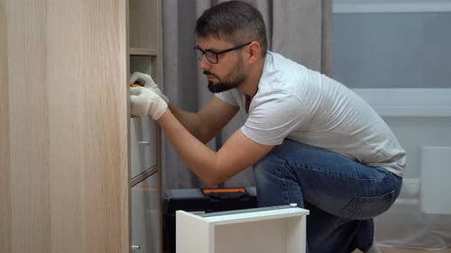 Man Installs Drawer in Wardrobe Using Screwdriver Handyman Assembles Furniture