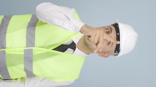 Vertikales Video von Der Ingenieur schaut nach oben und hält seinen Schutzhelm in der Hand.
