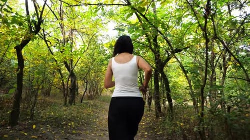 Adult Brunette Woman Running Along Path at Summer Forest Lady Jogging Among Trail at Wild Nature