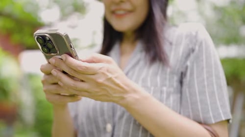 Close-up of a woman's hand using a cell phone to send a message to friends.