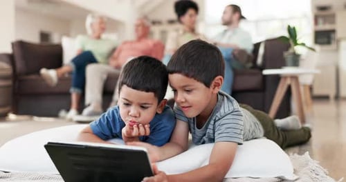 Boys Using Tablet with Family in Background