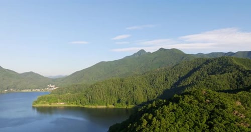 Drone shot of the mountainous coastline of lake Kawaguchi, sunny day in Japan