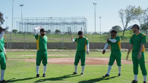 Diverse male teammates performing warm-up stretches on baseball field, with batting cage backdrop