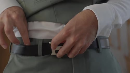 Man adjusting belt and formal suit