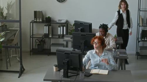 Young Woman Coming up to Female Colleague during Workday in Call Centre