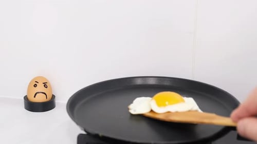 Die Hand eines Mannes dreht Rühreier mit einem Holzstab um
