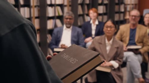 Unrecognizable Author Holding New Book, Presenting It in Library