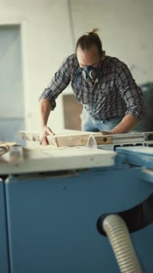 Woodworker with Respirator Mask Cutting a Wood Plank