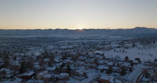 Drone shot of the sun setting over the Rocky Mountains in Denver, CO on a snowy winter day.