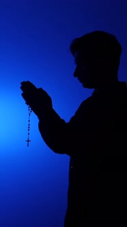 Silhouette of Man Praying with Rosary Beads