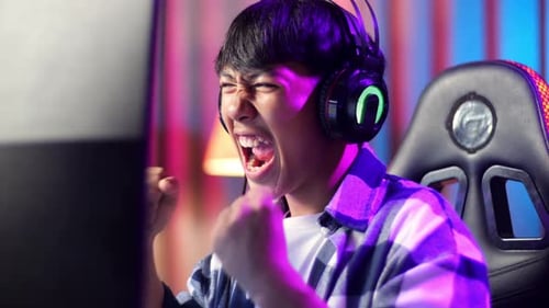 Close Up Of Excited Asian Teen Boy Gamer Celebrates Victory While Playing Video Game On Computer