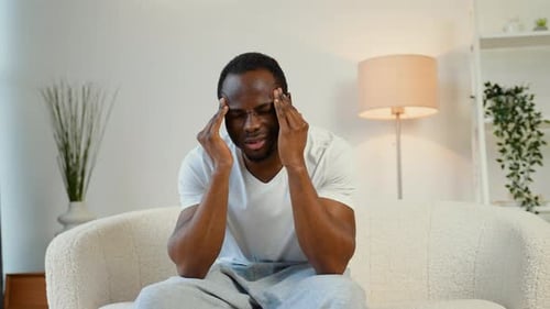 Man Rubbing Temples Experiencing Headache at Home