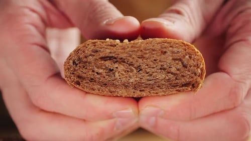 Hands Tear a Seeded Roll in Half