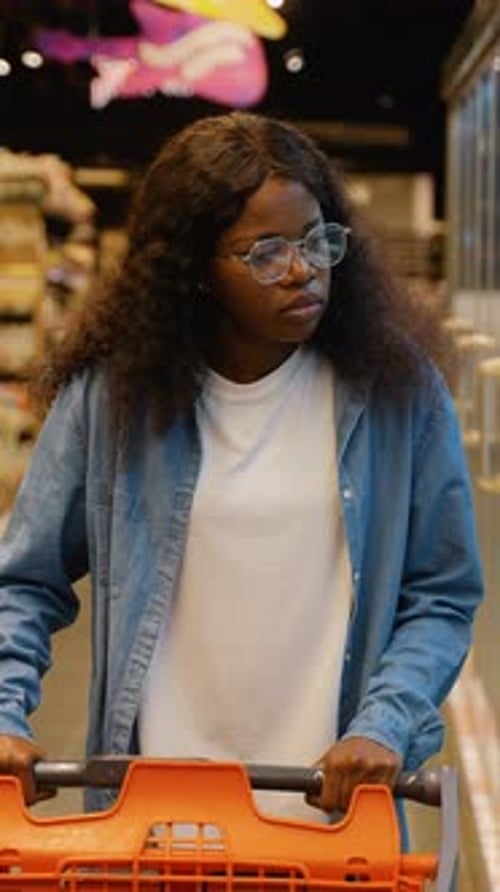 African American Woman Shopping with Cart in Supermarket