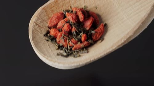 Dried Goji Berries Adding in Tea in Bowl and Spoon on Wooden Table Close Up