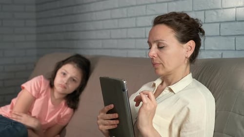 Woman Uses Tablet, Sad Girl on Couch