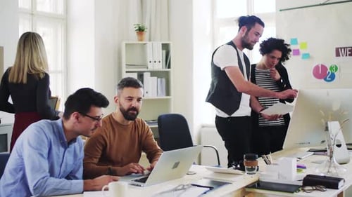 Group of Young Businesspeople with Laptop Working Together in a Modern Office