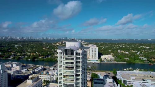 Aerial video of a high rise building with a beach front on a bright sunny day.