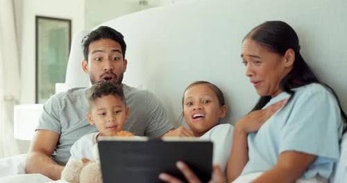 Family Watching Tablet Together in Bedroom at Home