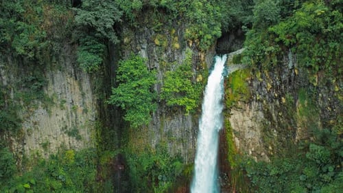 Blue Falls waterfall spills from cliffside into deep jungle gorge in Costa Rica