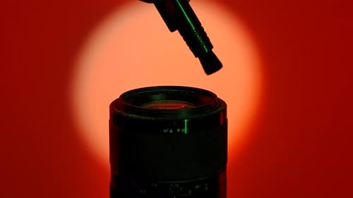Silueta de una mano que sostiene el cepillo cerca de la lente de la cámara bajo una luz de neón