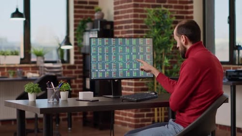 Man Works At Desk Analyzing Stock Market Data