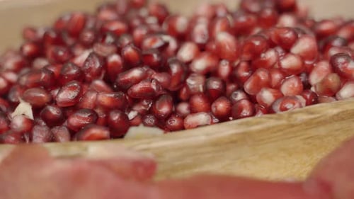 Slow pan across pomegranate seeds inside of wooden plate juicing and using fresh ingredients and fre