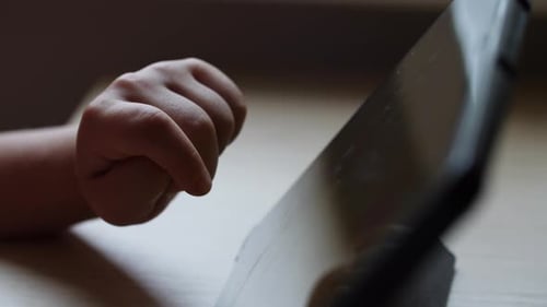 Child's Hand Taps Tablet Screen in a Game Detailed View