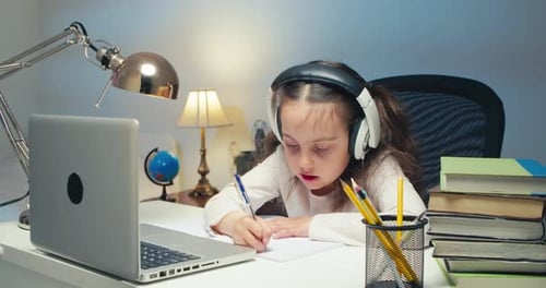 Child Studies at Desk with Laptop and Headphones