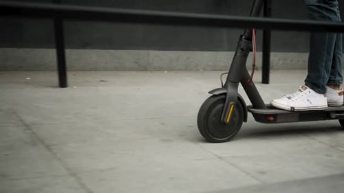 Schöner junger Geschäftsmann mit Elektroroller auf einer Straße