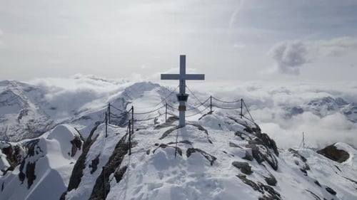 Close up drone shot of summit cross on snowy mountain peak of Kitzsteinhorn during sunny day in Aust