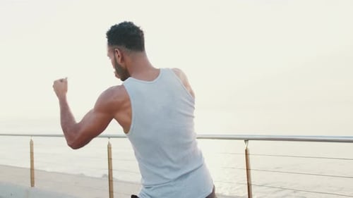 Young fit athlete boxer practicing punching technique while standing on the embankment