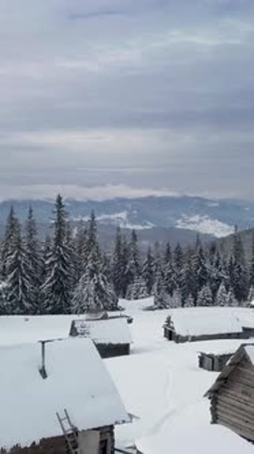 Aerial View of SnowCovered Pine Trees and Cabins in Tranquil Mountain Landscape at Sunrise
