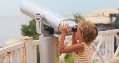 Child Using Telescope to See Ocean Views