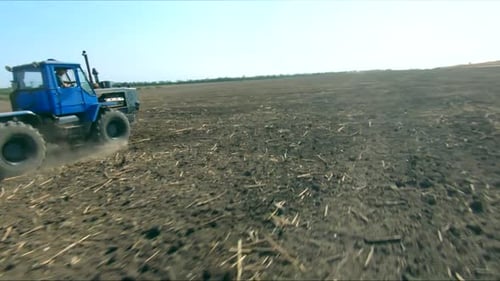 Aerial Shot of Tractor with Harrow System Plowing Ground on Cultivated Farm Land Processing the