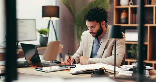 Young Adult Writes in Office at Desk