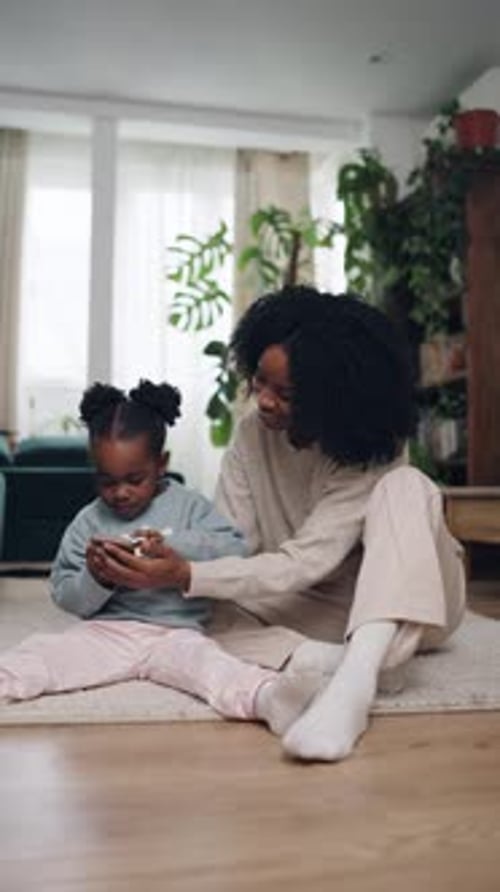 Child and Woman Using Mobile Device Together Indoors