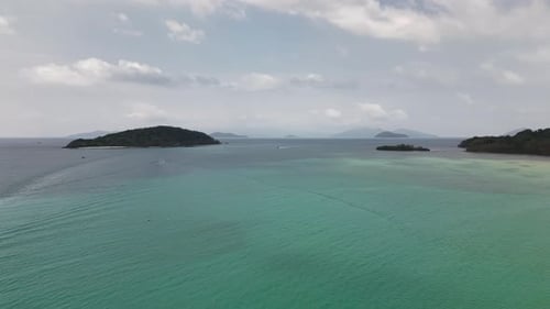 Aerial view of turquoise sea with tropical islands scattered across horizon as speedboat glides crea