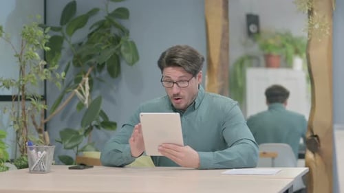 Man Working On Tablet Device Displaying Frustration