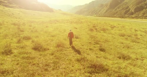Flight Over Backpack Hiking Tourist Walking Across Green Mountain Field Huge Rural Valley at Summer
