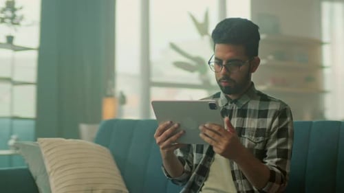 Young Adult Using Tablet on Sofa at Home