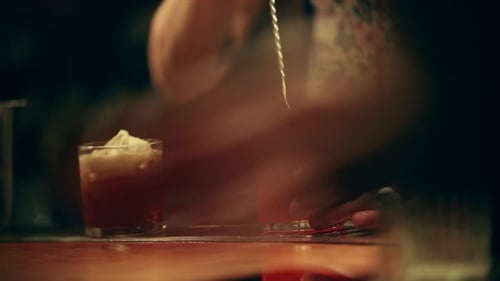 Bartender Stirring Red Cocktail with Ice at Bar
